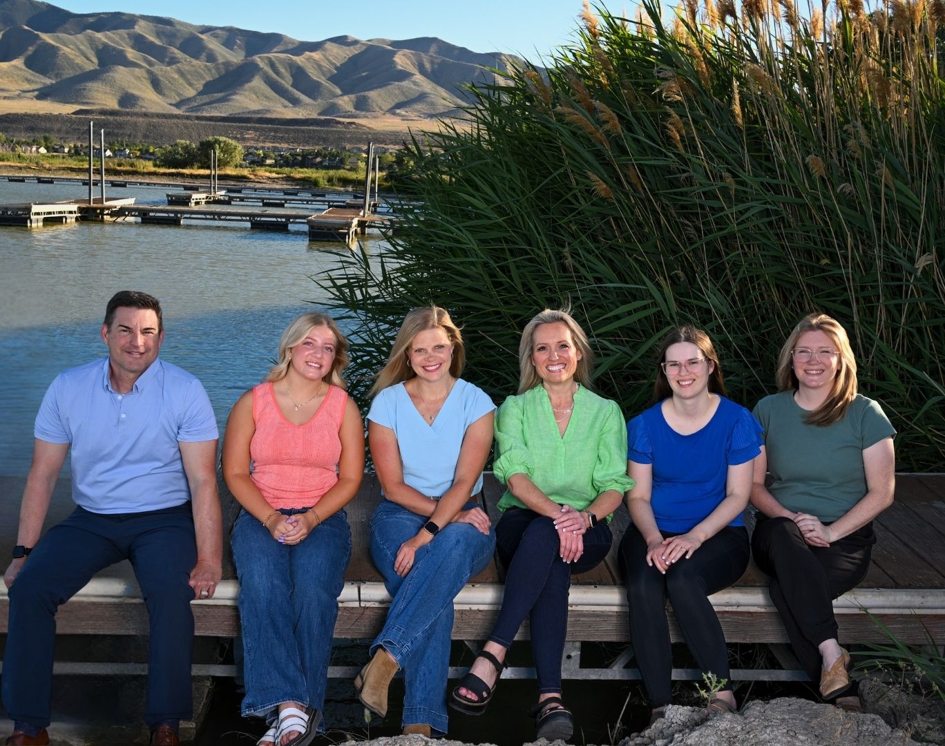 The Vibrant Life Therapy team gathered beside a lake with mountains in the background
